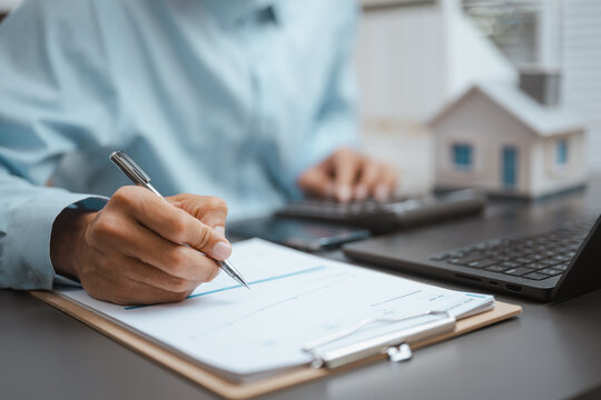 Realestate property costs shape a mortgage for real estate funded by a loan as hands write on paper, checking realestate property costs for a mortgage and real estate terms under a loan by the model.