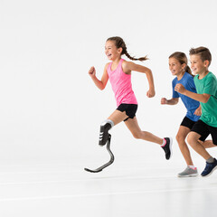 Obraz premium Young girl with prosthetic leg running with friends on a track