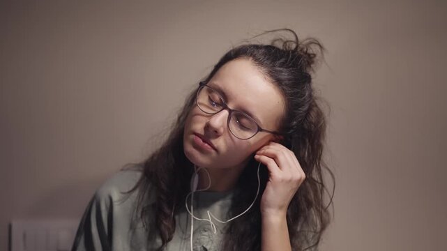 Excited woman with long curly hair and glasses dancing crazy laughing and yelling into her earbuds, enjoying herself on favour music