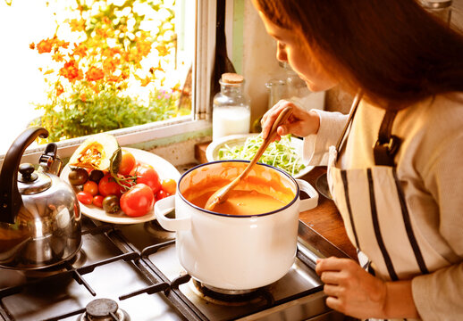 Woman cooking soup in cozy kitchen setting
