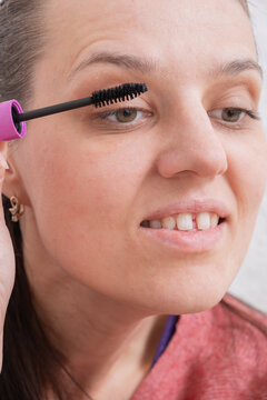 Woman applying mascara in front of a mirror during a beauty routine at home