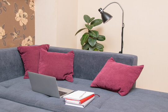 Cozy living room setup with laptop and notebooks on a soft couch