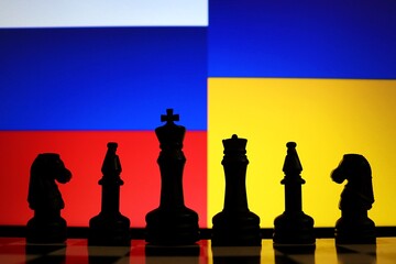 Russia and Ukraine flags behind chess knight pieces. International relations, war concept. © Blossom Stock Studio