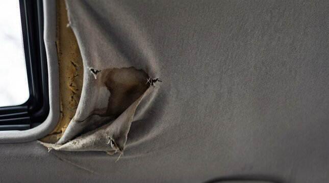 Damaged car headliner fabric peeling away from the vehicle interior roof panel