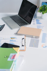 Workspace Efficiency: A well-organized desk featuring a laptop, documents with charts, a notebook,...