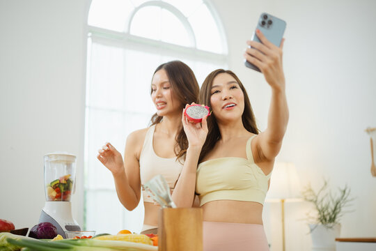 Two healthy women hold cut ripe dragon fruit as social sharing places media in an online stock context, while healthy women holding a phone upright use social cues around media for an online context.