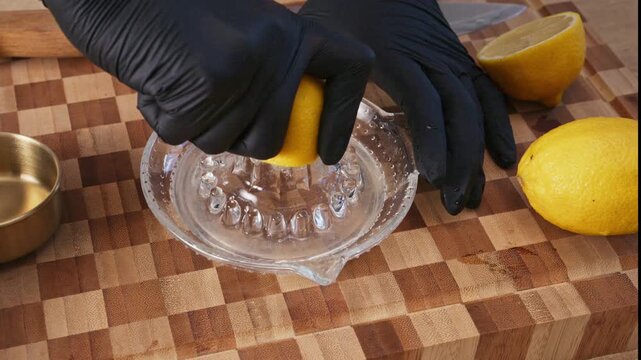 Hands squeezing fresh yellow lemon on manual glass citrus juicer. Healthy organic citrus drink and vitamin C recipe, lemonade preparation.
