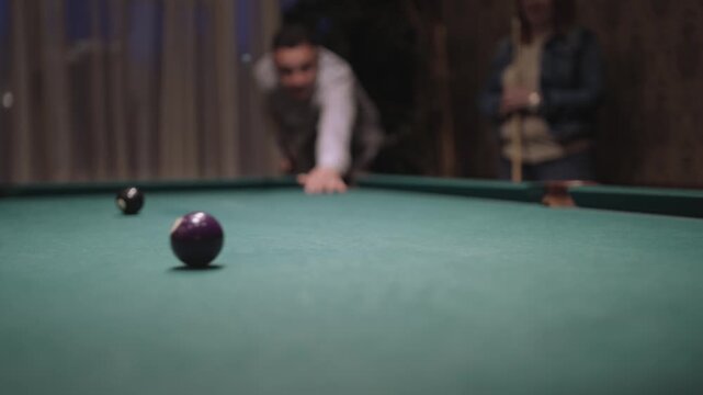 A man is playing pool and is about to hit the ball with the cue, isolated slow motion shot