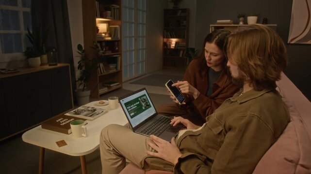 Caucasian young couple browsing web using laptop and smartphone while discussing online shopping. Clip suits e-commerce advertising, retail promos, and digital consumer lifestyle marketing