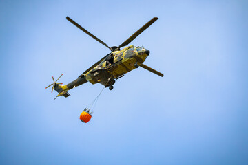 Fototapeta premium Firefighting helicopter carrying a water tank