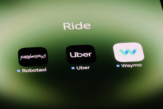 Shanghai,China-Sep.6th 2026: ride-hailing and autonomous taxi app icons on phone screen, including Tesla Robotaxi, Uber, and Waymo.