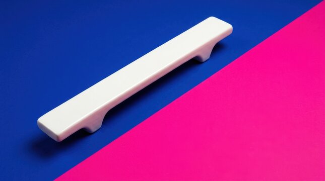 A white drawer handle is placed diagonally on a blue and pink surface emotional health