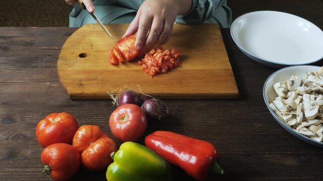 A woman's hands cut fresh red tomatoes with a knife