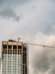 Modern skyscraper under construction with tower crane against cloudy sky. Urban development, real estate growth, and civil engineering concept. © LemPro Filming Life