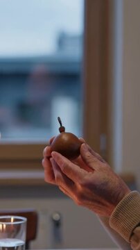 Vertical video: Giving ornament, hands in cream and beige sleeves exchanging at dining table