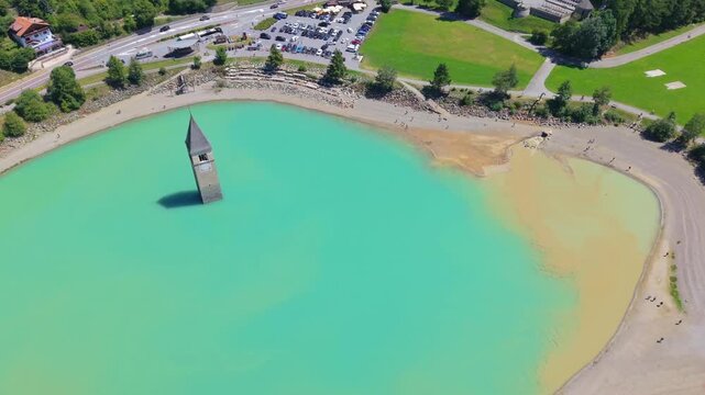 Aerial view of the iconic submerged church tower of Curon Lake Resia, in South Tyrol, Italy drone fly above the bell tower , famous travel destination