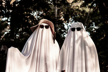 A couple wearing ghost costumes stands outdoors during Halloween © Amely