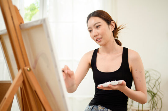Woman Painting on a Canvas in a Bright Room With Large Windows