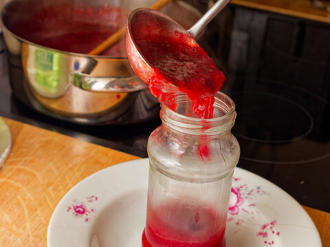 Pouring plum marmalade in glass jar