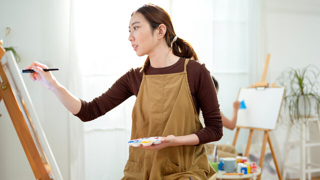 Woman Painting on a Canvas in a Bright Room With Large Windows