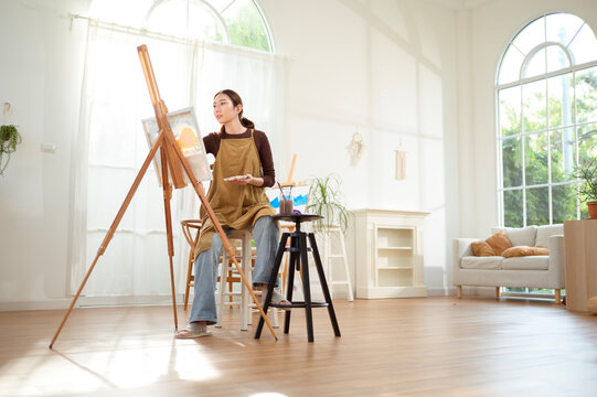 Woman Painting on a Canvas in a Bright Room With Large Windows