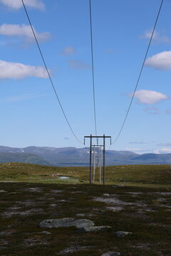 Alpine plateau at Flatruet with wooden utility poles and power lines on a sunny summer day