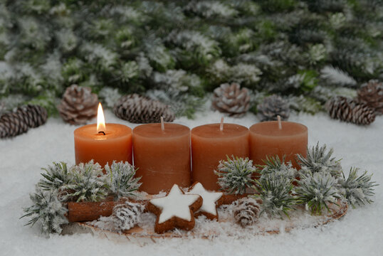 Nat&uuml;rliches Adventsgesteck auf einer Holzscheibe im Schnee.  Eine Kerze brennt f&uuml;r den 1. Advent.