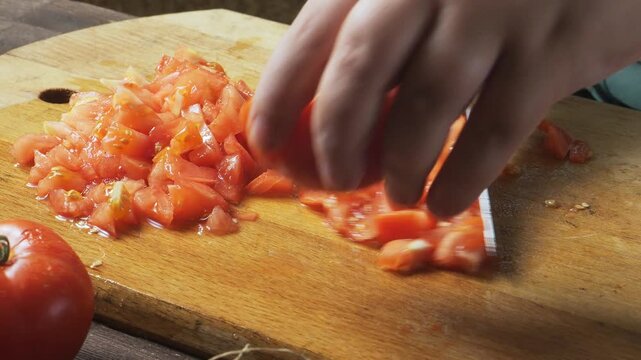 A woman's hands cut fresh tomatoes with a knife on a cutting board