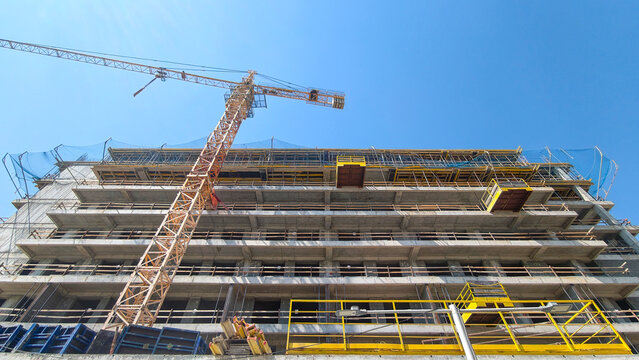 Concrete structure rising with a tower crane, symbolizing growth, investment, and the ongoing development of modern real estate and urban infrastructure projects