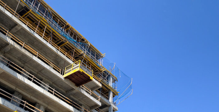 Concrete high rise building under construction against clear blue sky, demonstrating urban development, new property investment, and modern architectural progress