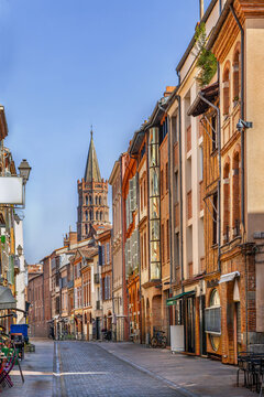 Street view of the old town in Toulouse, France. Perspective on the octagonal bell tower of Saint-Sernin under blue sky