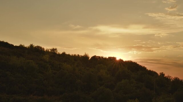 Sunset sunburst over forested Altai hillside, Kazakhstan