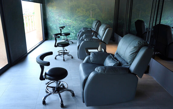 Row of massage chairs with footstools inside modern spa treatment room featuring soft upholstery.
