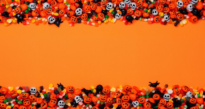Halloween candy and decorations on an orange background with space for text.
