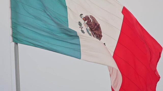 Large Mexican Flag Waving Against Cloudy Sky At Zocalo In Mexico City
