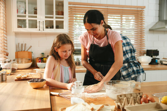 Family cooking concept with parents and daughter preparing homemade food together in a bright kitchen, sharing baking skills and quality time. family, cooking, kitchen, baking, together