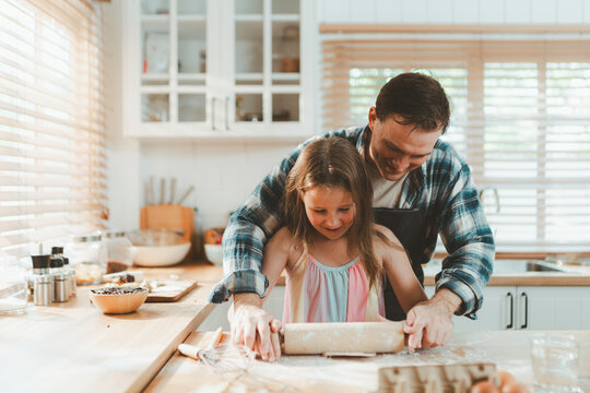 Family cooking concept with parents and daughter preparing homemade food together in a bright kitchen, sharing baking skills and quality time. family, cooking, kitchen, baking, together