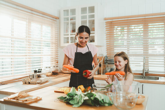 Family cooking concept with parents and daughter preparing homemade food together in a bright kitchen, sharing baking skills and quality time. family, cooking, kitchen, baking, together
