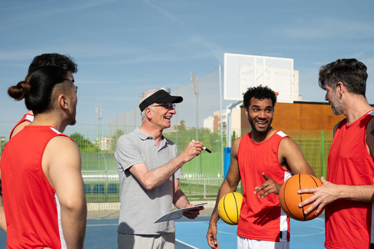 Basketball coach discussing strategy with his multi ethnic team on an outdoor court
