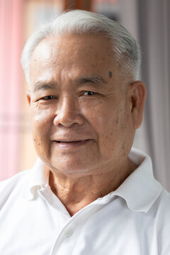 southeast asian senior man face portrait with happy mood and a gentle smile, indoor scene with natural window light