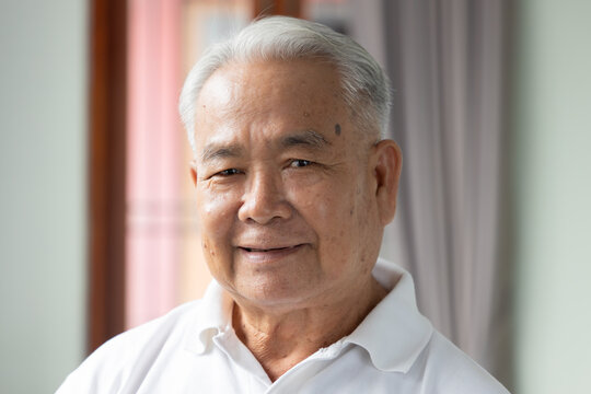 southeast asian senior man face portrait with happy mood and a gentle smile, indoor scene with natural window light