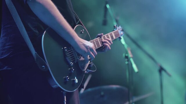 A person playing an electric guitar in slow motion in front of a microphone at night concert performance