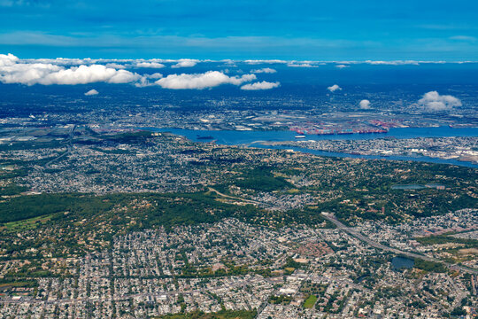 Aerial view of Staten Island with Newark Bay and Newark in the background, showcasing urban residential areas and shipping port facilities stretching towards the horizon in New York and New Jersey.