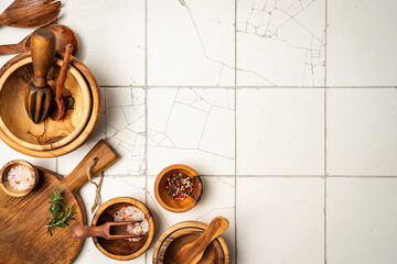 Obraz premium Old wooden kitchen utensils or cooking tools and bowls on white tile background, top view, flat lay. Kitchenware collection with copy space. Cooking background.