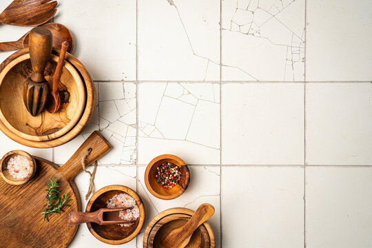 Old wooden kitchen utensils or cooking tools and bowls on white tile background, top view, flat lay. Kitchenware collection with copy space. Cooking background.