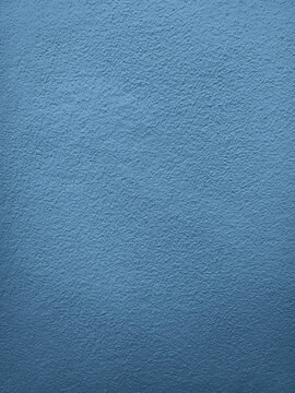 Close up photograph of a vintage blue concrete wall featuring rough textured surface and muted cool color, ideal for backgrounds, design projects, architecture, and decorative concepts.