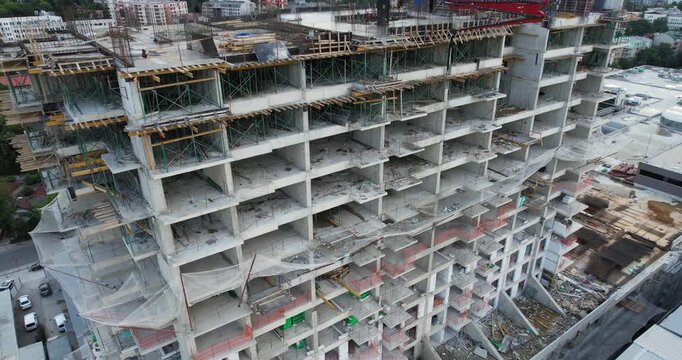 A building under construction with scaffolding and a tarp covering the top. The building is tall and has many windows