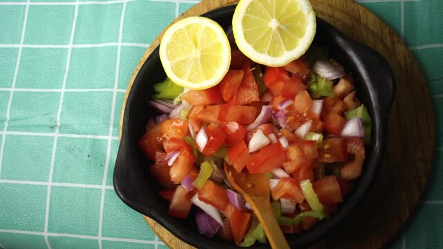 Panning view of freshly made pebre salsa in a ceramic bowl with lemon half