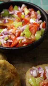 Panning view of a rustic platter with homemade sopaipillas and fresh pebre sauce, vertical view