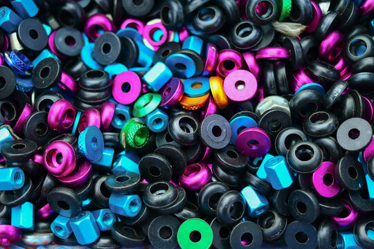 Colorful anodized aluminum washers, aluminum hex nuts, and plastic washers arranged in a dense close up, creating vivid industrial hardware texture for DIY, design, and automotive content.